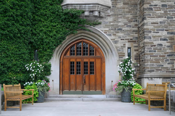 double porte d’entrée en bois avec verre au plomb et mur de pierre recouvert de lierre du bâtiment de style gothique collège - Photo