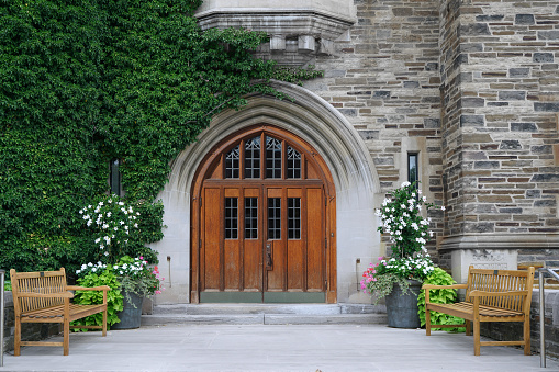 double wooden front door with leaded glass and ivy covered stone wall of gothic style college building