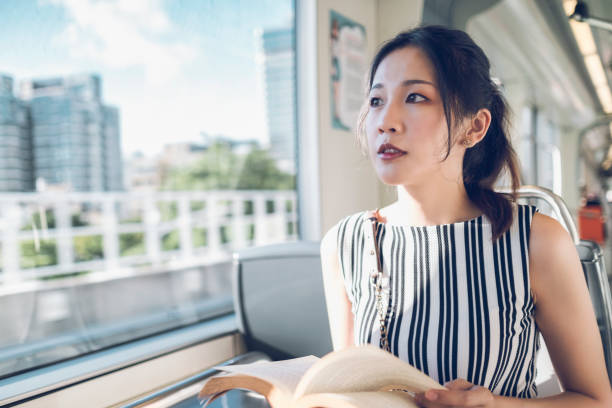 istock asian woman reading book in subway train 1268023049