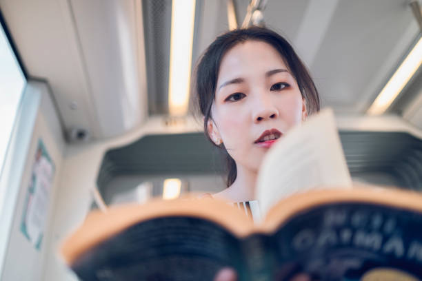 istock asian woman reading book in subway train 1268023108