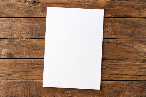 Empty white paper sheet on rustic wooden table. Top view