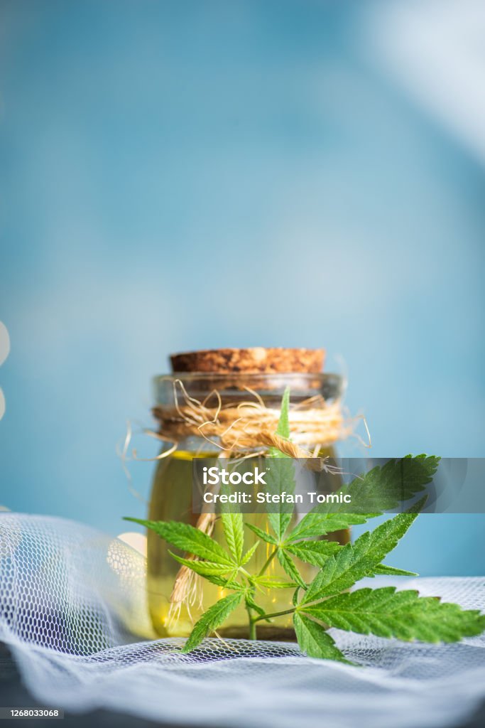 Cannabis medical oil packed in a small bottle Cannabis medical marijuana THC oil packed in a small bottle against blue background with copy space Cannabis - Narcotic Stock Photo