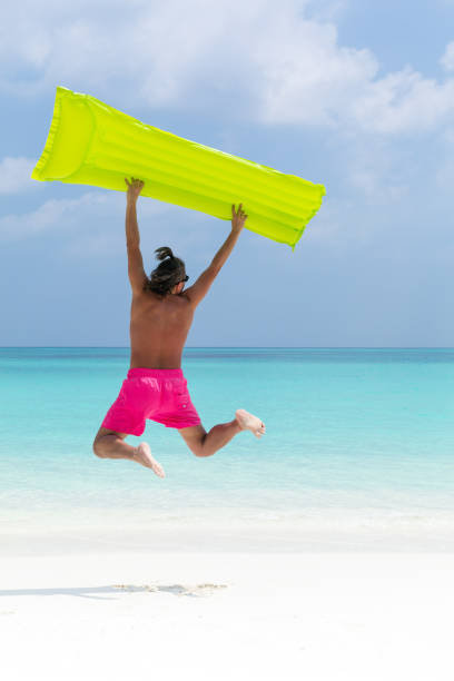 istock Man with inflatable green mattress on beach 1268036856