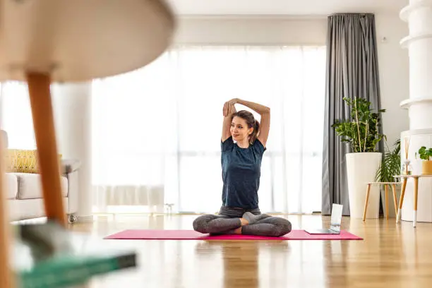 Attractive young woman doing yoga stretching yoga online at home. Self-isolation is beneficial, entertainment and education on the Internet. Healthy lifestyle concept.