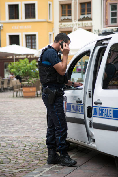municipal policeman at phone and police car on the main place Mulhouse - France - 22 August 2020 - Portrait of municipal policeman at phone and police car on the main place mulhouse photos stock pictures, royalty-free photos & images