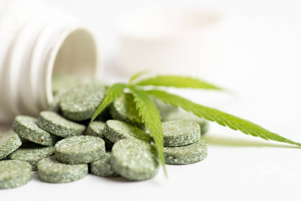 Medical tablet pills with cannabis and marijuana leaf Green medical tablet pills with infused cannabis oil and marijuana leaves closeup cannabinoid stock pictures, royalty-free photos & images