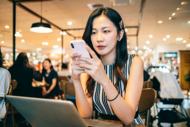 istock young Asian woman is using mobile phone in cafe. 1268039187