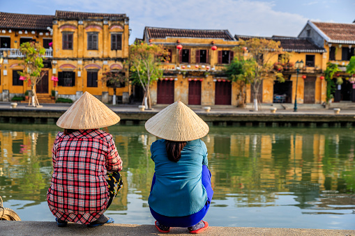Vietnamese women looking at old town in Hoi An city, Vietnam. Hoi An is situated on the east coast of Vietnam. Its old town is a UNESCO World Heritage Site because of its historical buildings.