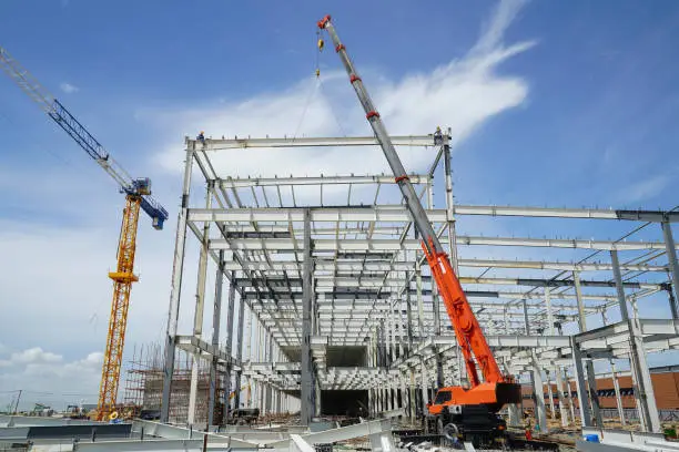 Structure building of steel structure roof truss frame installation by mobile crane under the construction building in the factory with blue sky
