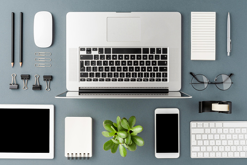 Overhead shot of laptop and business accessories on gray background. Office desktop.  Flat lay