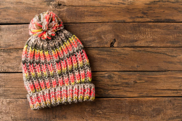 istock Colourful winter hat with pompon on rustic wooden background with copyspace. Top view 1268042976