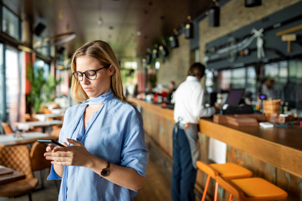 istock An Attractive Blonde Woman is Using her Mobile Phone for Online Browsing while Sitting in the Modern Café, but Looking Pensive. 1268047718