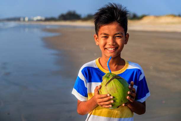 istock Vietnamese boy holding coconuts on the beach, Vietnam 1268049300