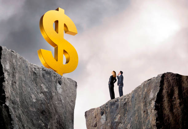 бизнесвумен и бизнесмен смотрят на большой знак доллара - cliff finance risk uncertainty стоковые фото и изображения