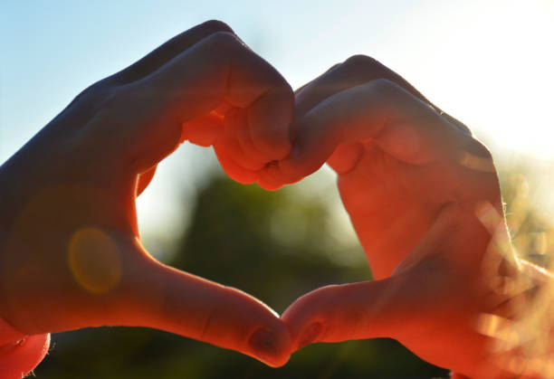 istock heart from female hands at sunset 1268052947