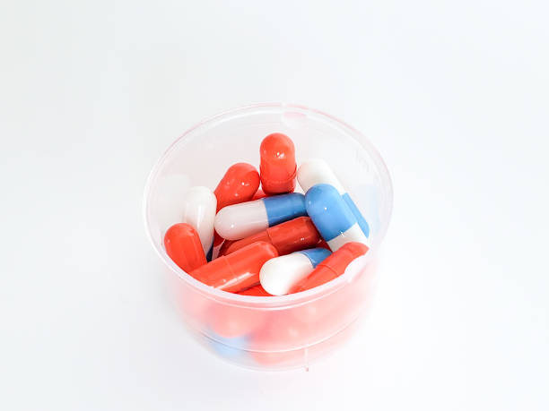 Capsules with medicine in a measuring Cup on a white background, close-up