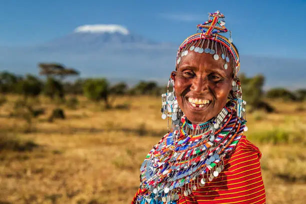 Portrait of happy African woman from Masai tribe, Kenya, Africa. Mount Kilimanjaro on the background, central Kenya, Africa. Maasai tribe inhabiting southern Kenya and northern Tanzania, and they are related to the Samburu.