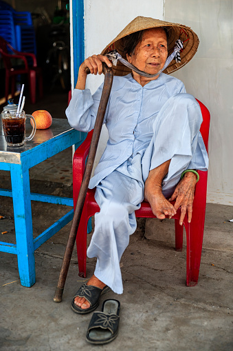 Senior Vietnamese woman drinking coffee, Mekong River Delta, Vietnam