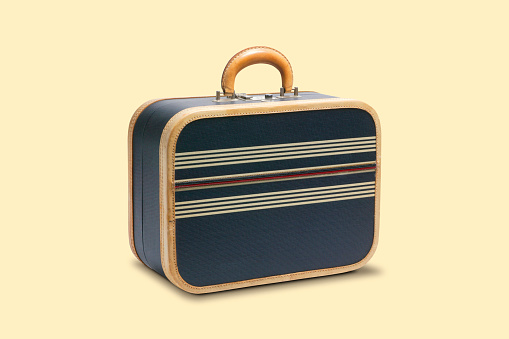 A 1950's style suitcase isolated on a yellow background.