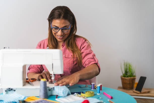 コロナウイルスの拡散を防止し、停止するための自家製医療フェイスマスクを行うミシンで働く女性 - テキスタイルの継ぎ目とヘルスケアの人々の概念 - embroidery sewing needle craft ストックフォトと画像