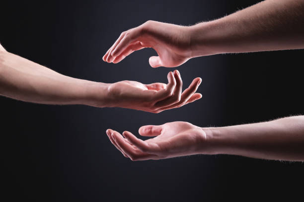 istock Close-up of a caring and helping hand on a black background. Helping and supporting hands concept symbolism 1268058988