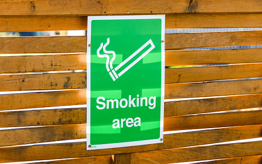 Close up of a sign marking a designated smoking area outside a premises. No people