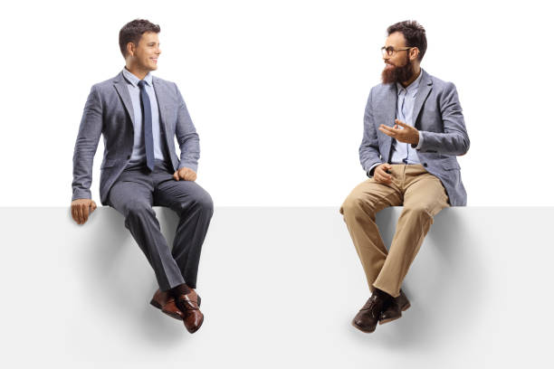 istock Two male friends sitting on a blank panel and talking 1268069094