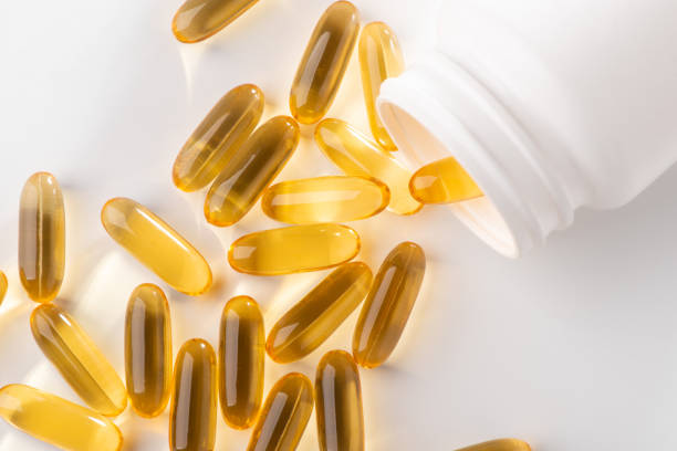 istock Yellow capsules scattered from a bottle on white background 1268070876
