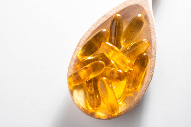 istock Close-up on cod liver oil capsules in a spoon on white background 1268070883