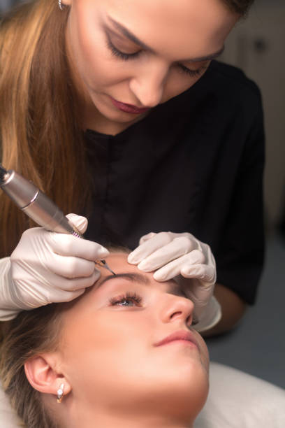 istock Permanent eyebrow makeup. Cosmetologist applying tattooing of eyebrows. 1268078609