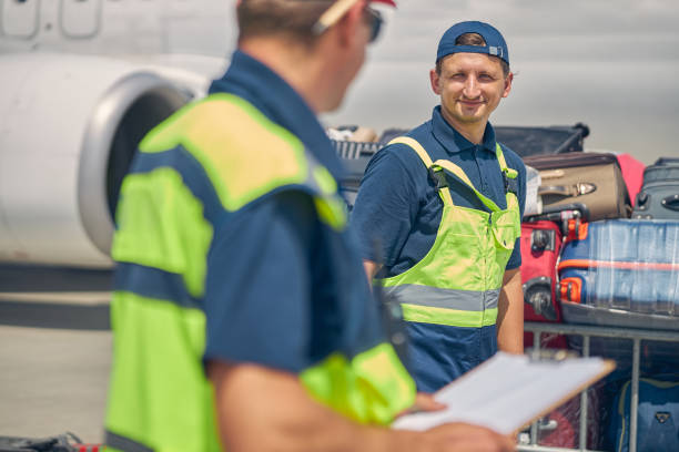 istock Baggage handlers standing by the carts loaded with suitcases 1268080029