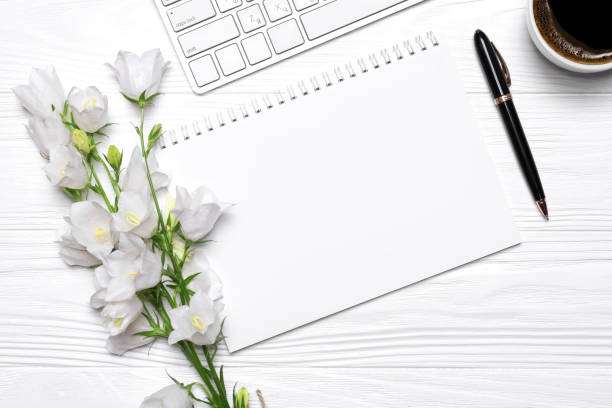 istock White flowers bells, coffee, pen, keyboard and empty notebook for your text on a white wooden background 1268081987