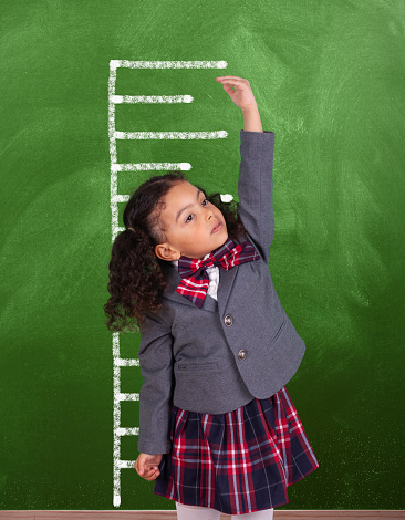 African schoolgirl is showing height on a blackboard scale