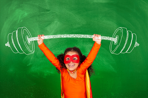 Weightlifting superhero girl in front blackboard