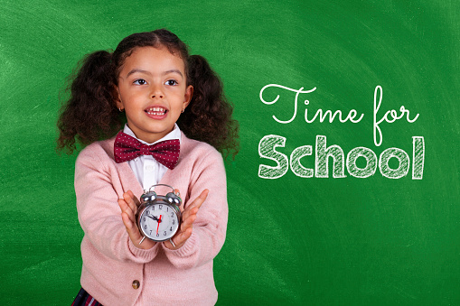 School African-American Child with Alarm Clock Show Time Back to School in front blackboard