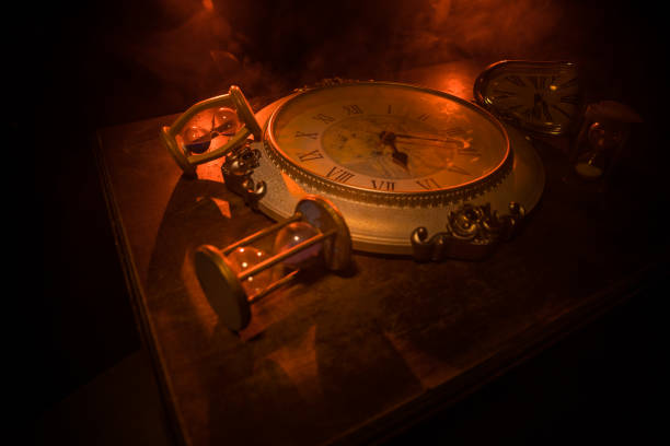 istock Time concept. Big vintage round clock on wooden table with abstract light. 1268110856