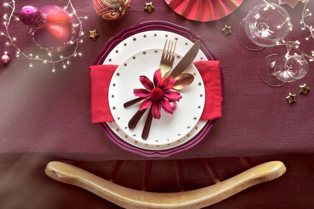 istock Christmas table setup with plates utensils, dark red and gilded decorations. Flat lay, top view on chair and table with burgundy linen textile tablecloth. 1268116644