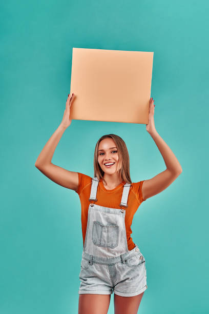 istock Blank sign. Young woman holding empty blank sign above her head. 1268119936
