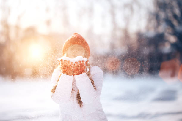 Happy young girl playind with snow and love winter, laughing and surprised, young woman in red hat throwing snow around, focus on snow.