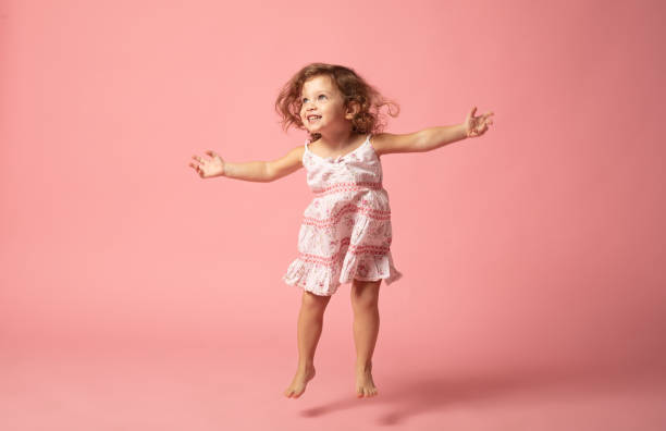 ragazza carina con salto a piedi nudi su sfondo rosa. - baby beautiful caucasian one person foto e immagini stock