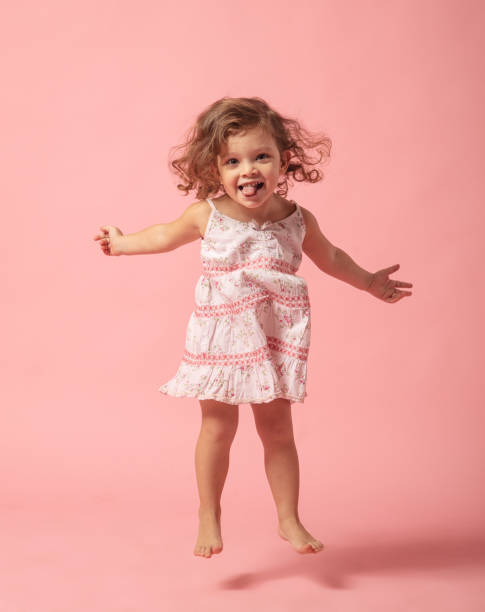 kuvapankkikuvat ja rojaltivapaat kuvat aiheesta söpö tyttövauva paljain jaloin hyppäämällä vaaleanpunaiselle taustalle. - one baby girl only