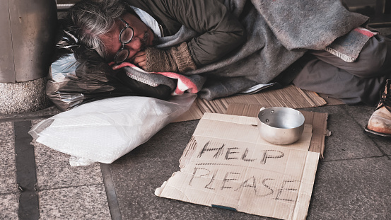 Homeless man sleeping on outdoor floor.