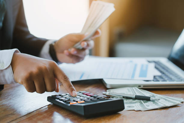 istock Businessman using calculator and holding money calculate Commerce Expense.Savings Finances Concept 1268149933