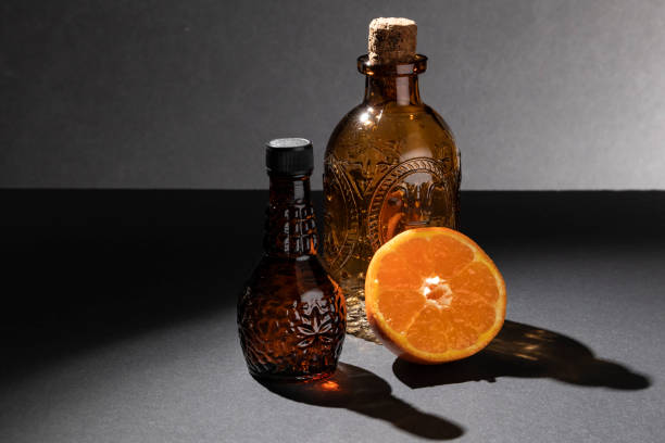 fotografía de tono oscuro. dos botellas de veneno o perfume con una naranja cortada. - antidote toxic substance ingredient bottle fotografías e imágenes de stock