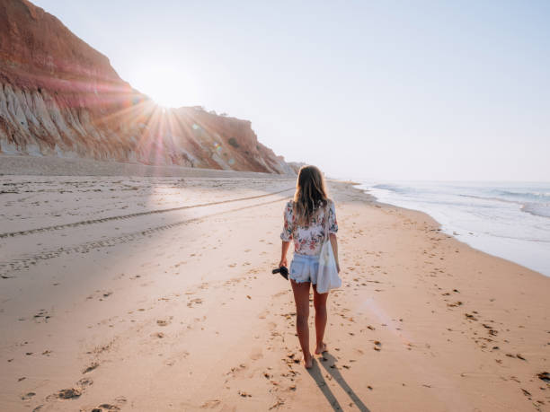 junge frau zu fuß am portugiesischen strand bei sonnenaufgang - atlantic coast stock-fotos und bilder