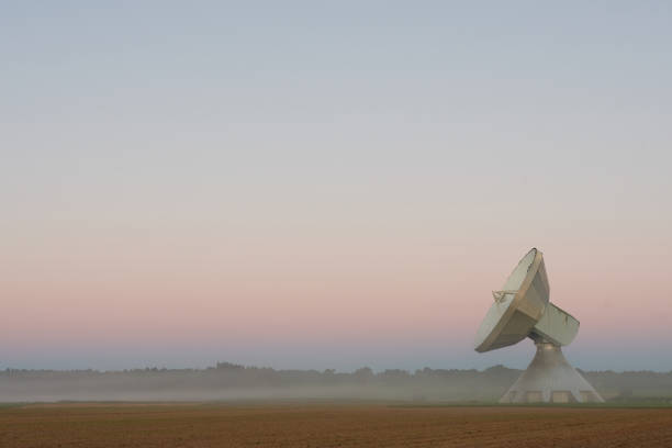The sun rises and the morning light is illuminating the antennas and the city of Raisting, Germany
