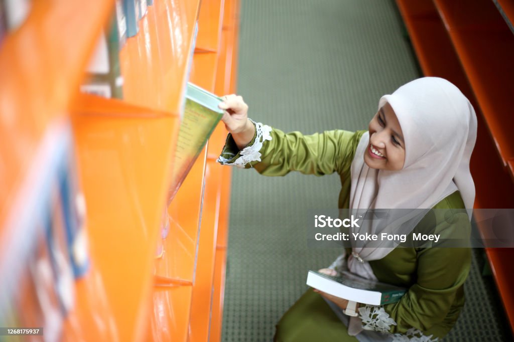 Library A Muslim female adult spending time reading in library. Book Stock Photo
