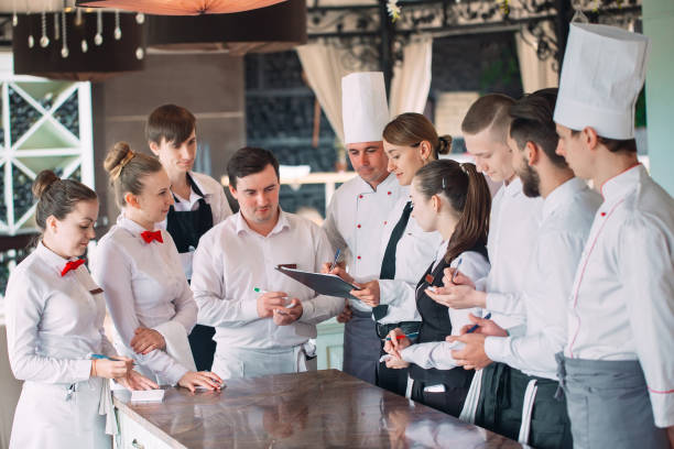 Restaurant manager and his staff in terrace. interacting to head chef in restaurant. stock photo
