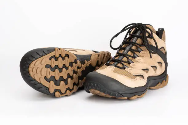 Pair of light brown women's hiking shoes made of leather, shoe sole visible. With a white background.