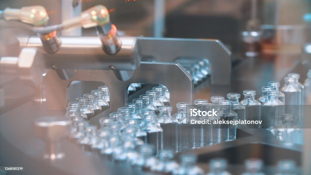 Glass bottles in production in the tray of an automatic liquid dispenser, a line for filling medicines against bacteria and viruses, antibiotics and vaccines Glass bottles in production in the tray of an automatic liquid dispenser, a line for filling medicines against bacteria and viruses, antibiotics and vaccines. Vaccination Stock Photo